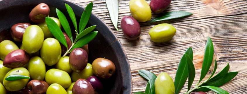 black and green olives placed in a bowl with olive leaves - Olive Oil Pour Spouts
