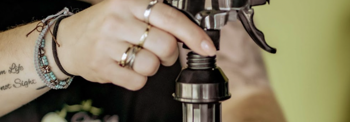 Person putting olive oil sprayer directly on olive oil bottle