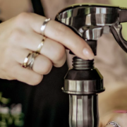 Person putting olive oil sprayer directly on olive oil bottle