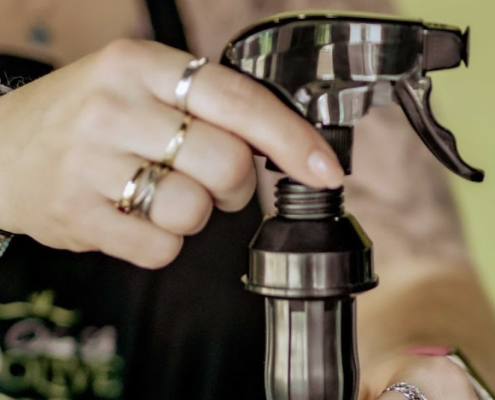 Person putting olive oil sprayer directly on olive oil bottle