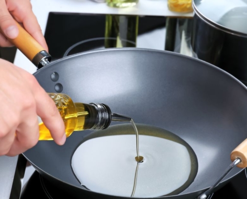person pouring oil into a cooking wok - Anytime Olive Oil Products wholesale olive oil pour spouts