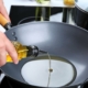 person pouring oil into a cooking wok - Anytime Olive Oil Products wholesale olive oil pour spouts