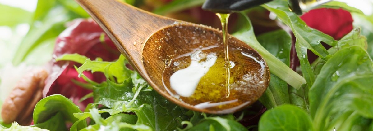 person pouring oil into a spoon over a salad - Anytime Olive Oil Products olive oil pour spouts