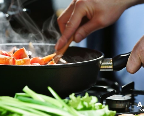 person stirring food in a fry pan - Anytime Olive Oil Products oil spout