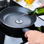 OliveOilPourSpouts-wholesale-olive-oil-pour-spouts-042520251 person pouring oil into a fry pan - Olive Oil Pour Spouts Commercial-Grade Olive Oil Spouts