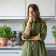 OliveOilPourSpouts-wholesale-olive-oil-pour-spout-061320251 woman wearing green dress thinking in her kitchen - Olive Oil Pour Spouts wholesale olive oil pour spouts