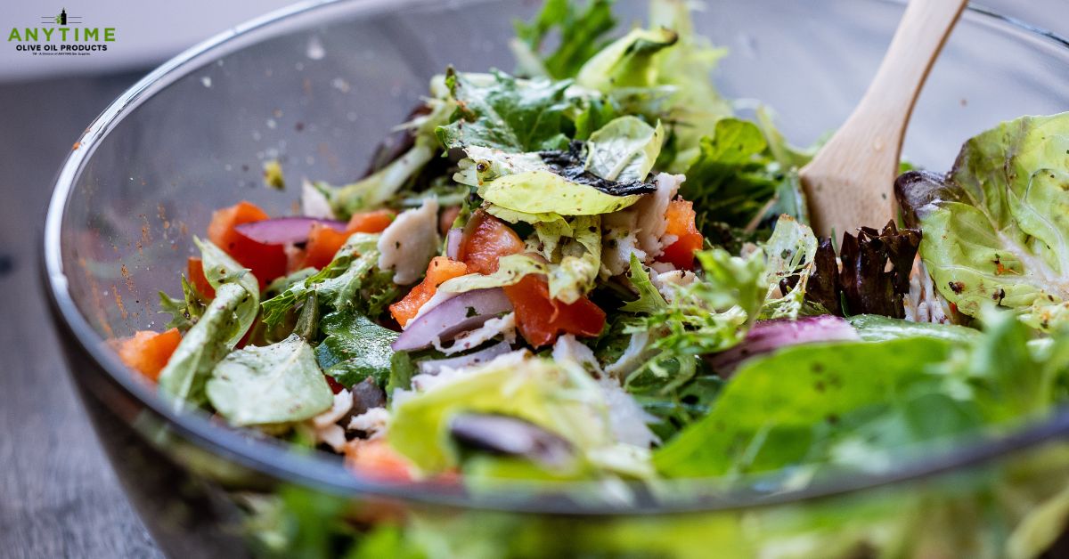 bowl with a vegetable salad and a wooden spoon - Anytime Olive Oil Products oil pour spout
